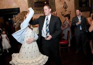Woman in white dress dancing with man in black suit at a formal indoor event