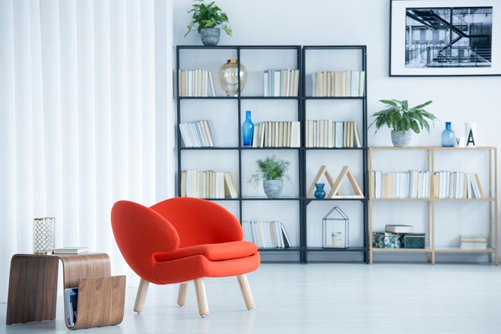 A Living Room with A Red Chair and A Bookshelf — Fraser Coast Waterproofing in Kawungan, QLD