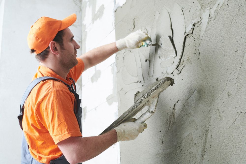 A Man Is Plastering a Wall with A Trowel — Fraser Coast Waterproofing in Kawungan, QLD