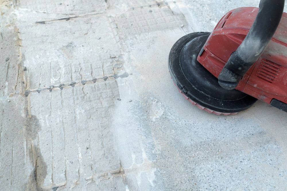 A Person Is Using a Grinder on A Concrete Floor — Fraser Coast Waterproofing in Pialba, QLD