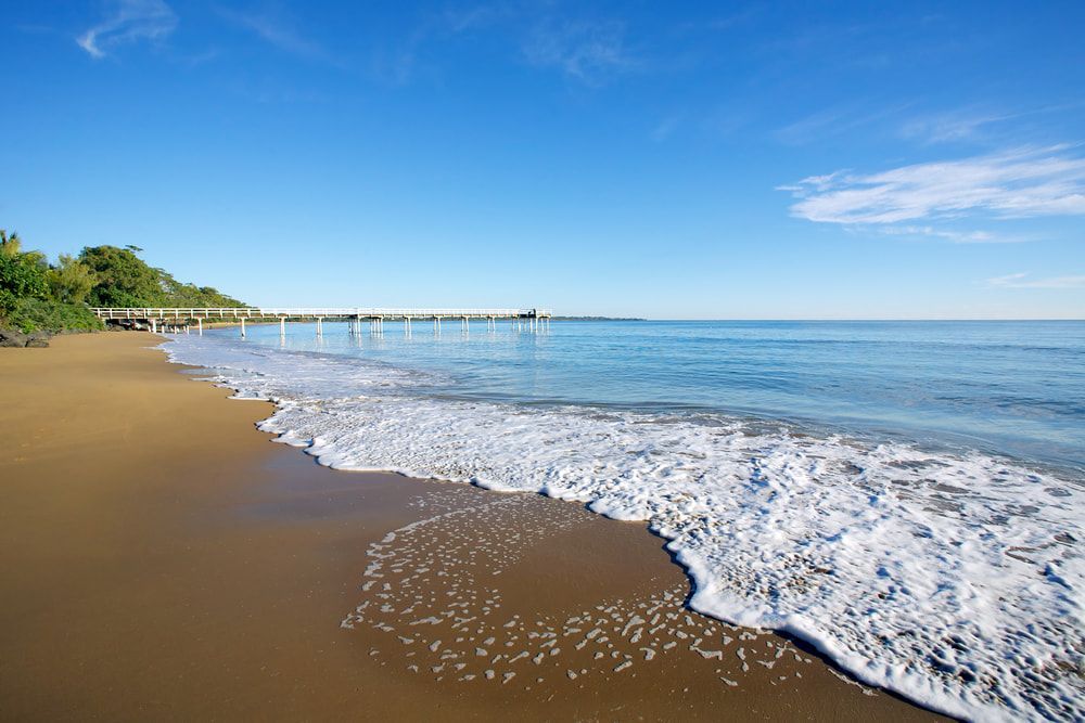 A Beach with Waves Crashing on The Sand on A Sunny Day — Fraser Coast Waterproofing in Hervey Bay, QLD
