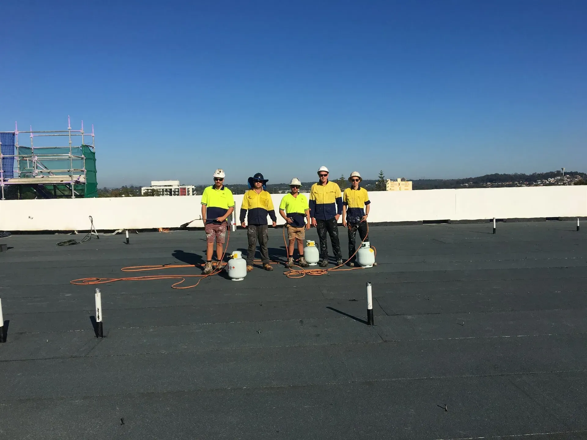 A group of workers are standing on top of a roof — Fraser Coast Waterproofing in Pialba, QLD