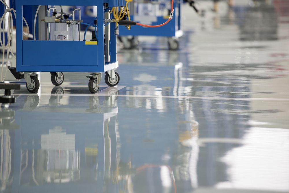 A Blue Cart Is Sitting on A Shiny Floor in A Factory — Fraser Coast Waterproofing in Urraween, QLD