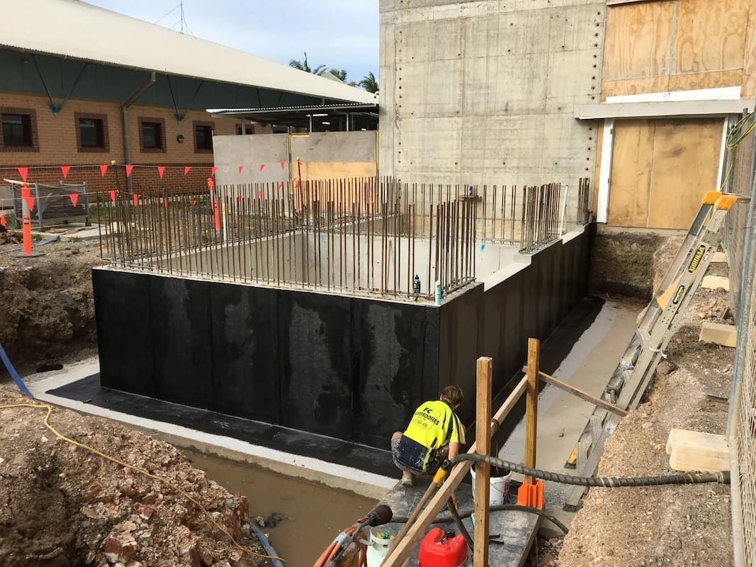 A Man Is Standing in Front of A Large Concrete Wall — Fraser Coast Waterproofing in Craignish, QLD