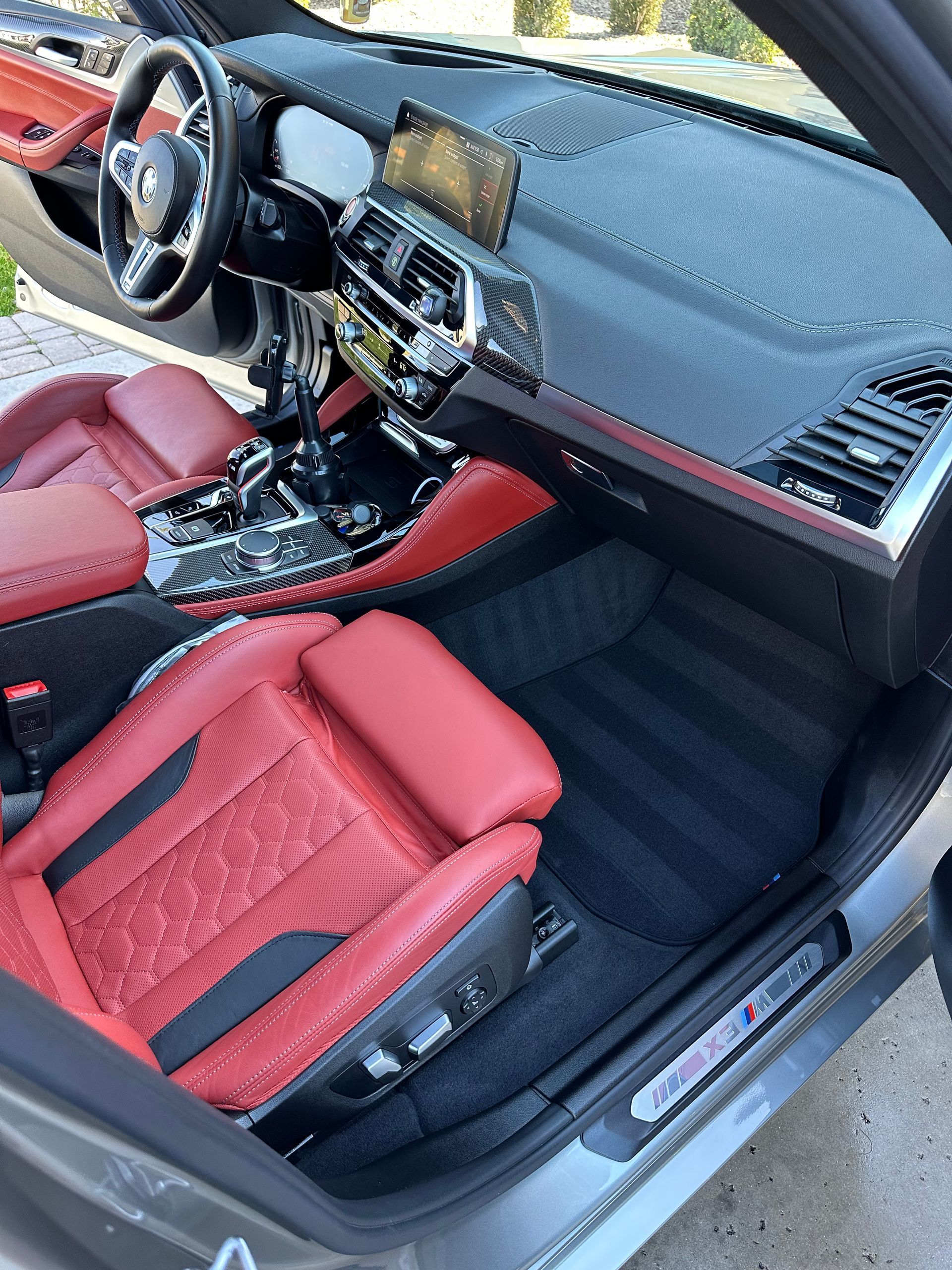 A person in a blue uniform and gloves uses an extraction tool to deep clean a textured black and gray car seat.