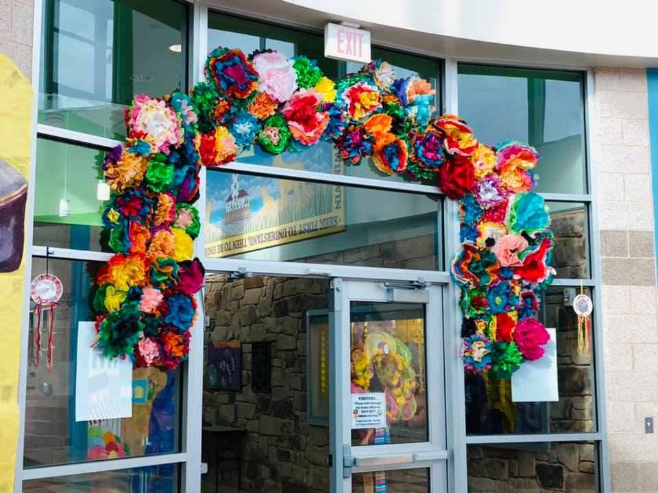 Colorful floral arch framing a storefront entrance with glass doors and windows