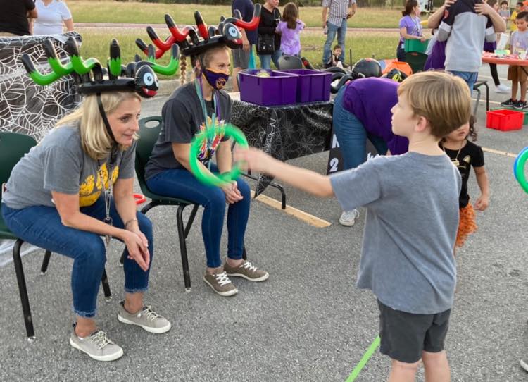 Children at an outdoor fair, interacting with a colorful balloon animal
