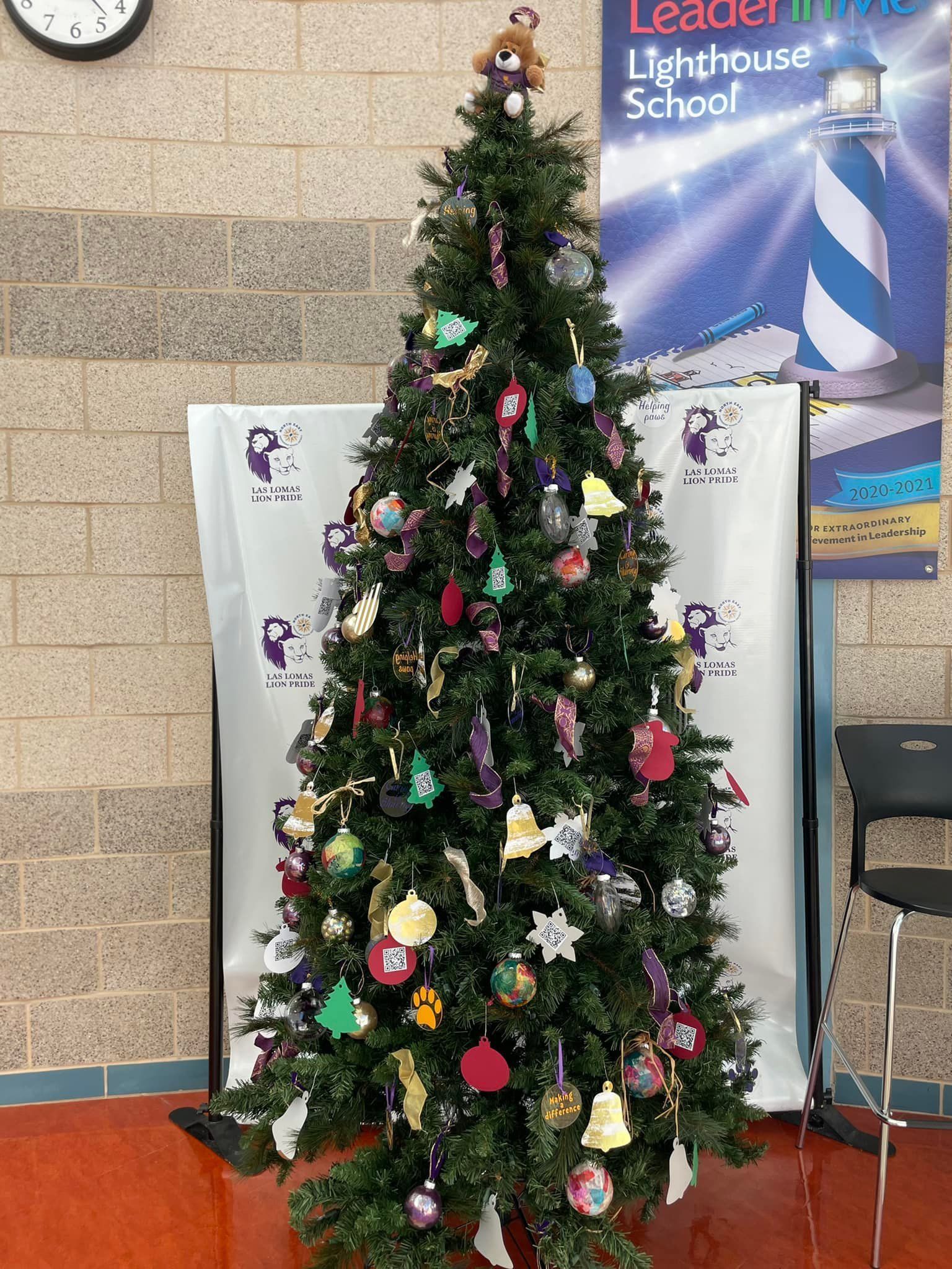 Decorated Christmas tree with ornaments and lights in a school lobby