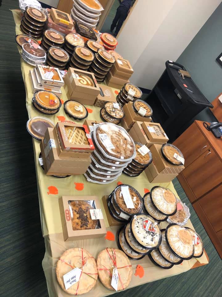 Table of assorted cakes and desserts in a room, with stacks of round and square boxes and trays.