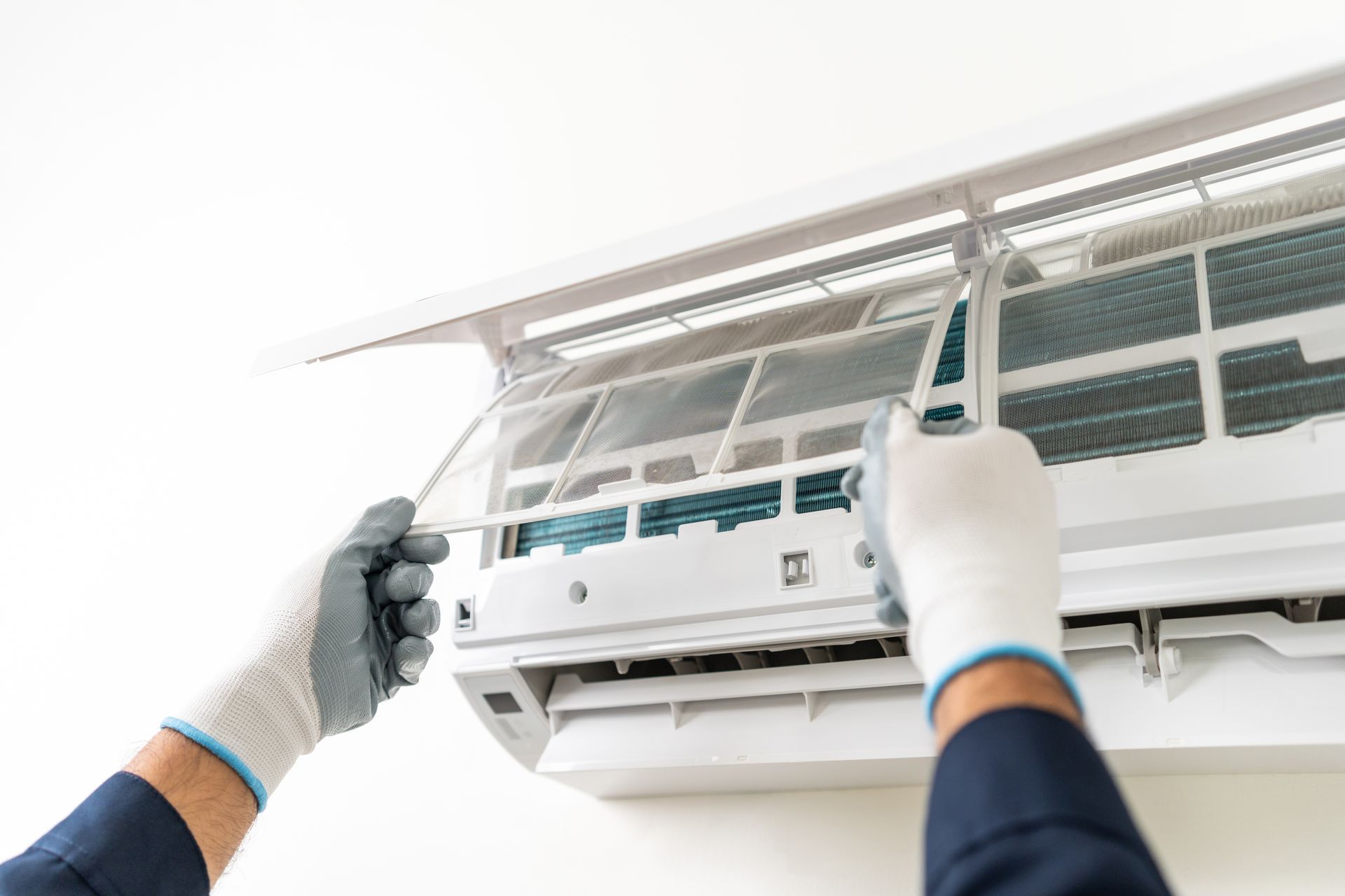 Person cleaning an air conditioner filter with gloved hands