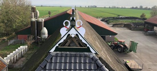 Uitzicht vanaf het dak van een gebouw met uitzicht op een boerderij, een tractor en akkers.