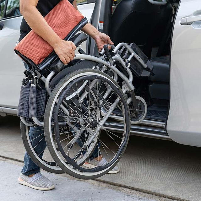 a person is loading a wheelchair into a car .