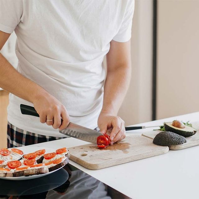 a man is cutting tomatoes on a cutting board in a kitchen .