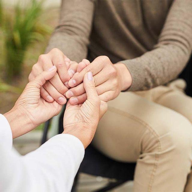 a woman is holding the hand of a man in a wheelchair .