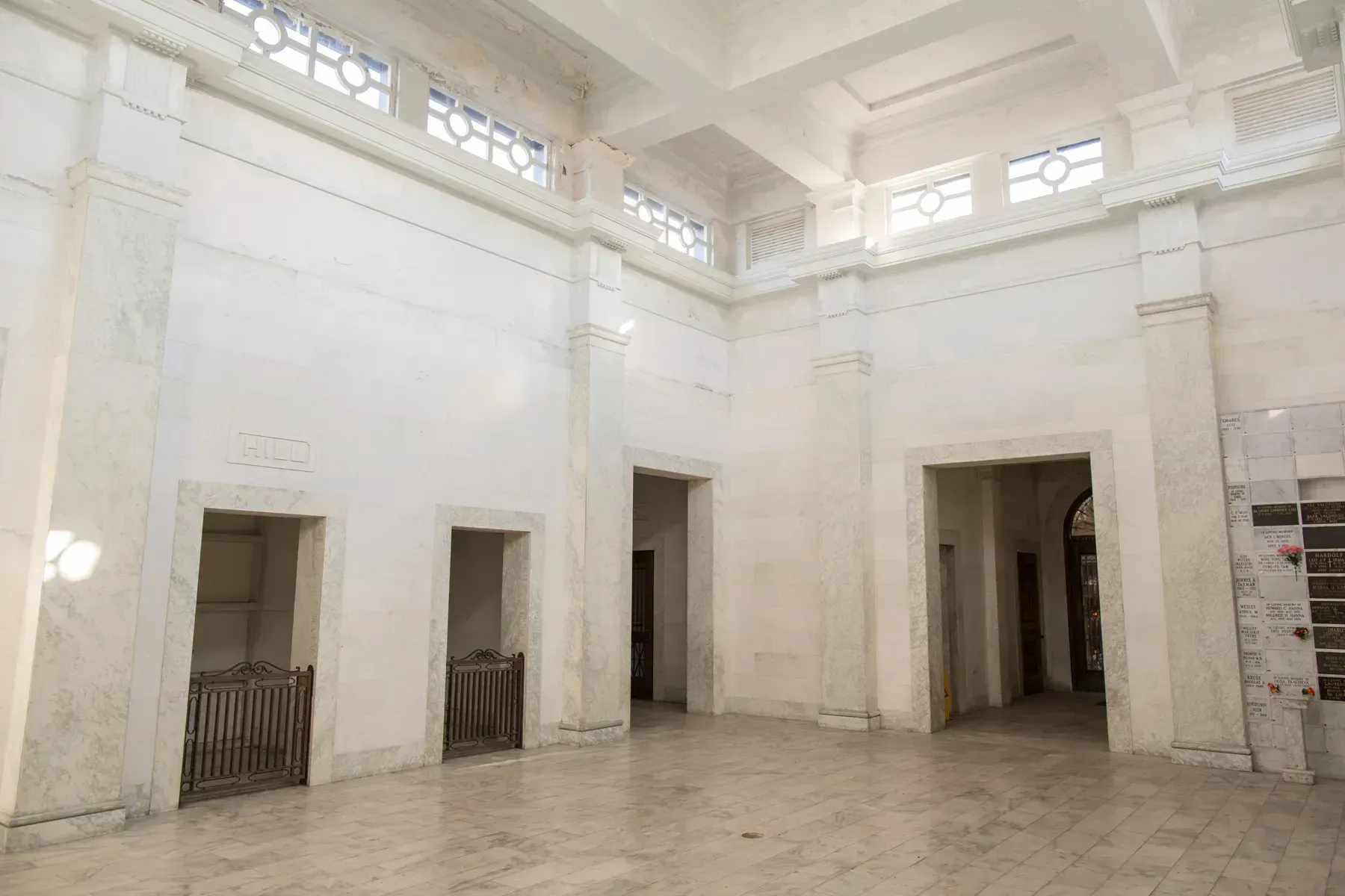 Bright white interior hall with tall doorways, tiled floor, and skylights above