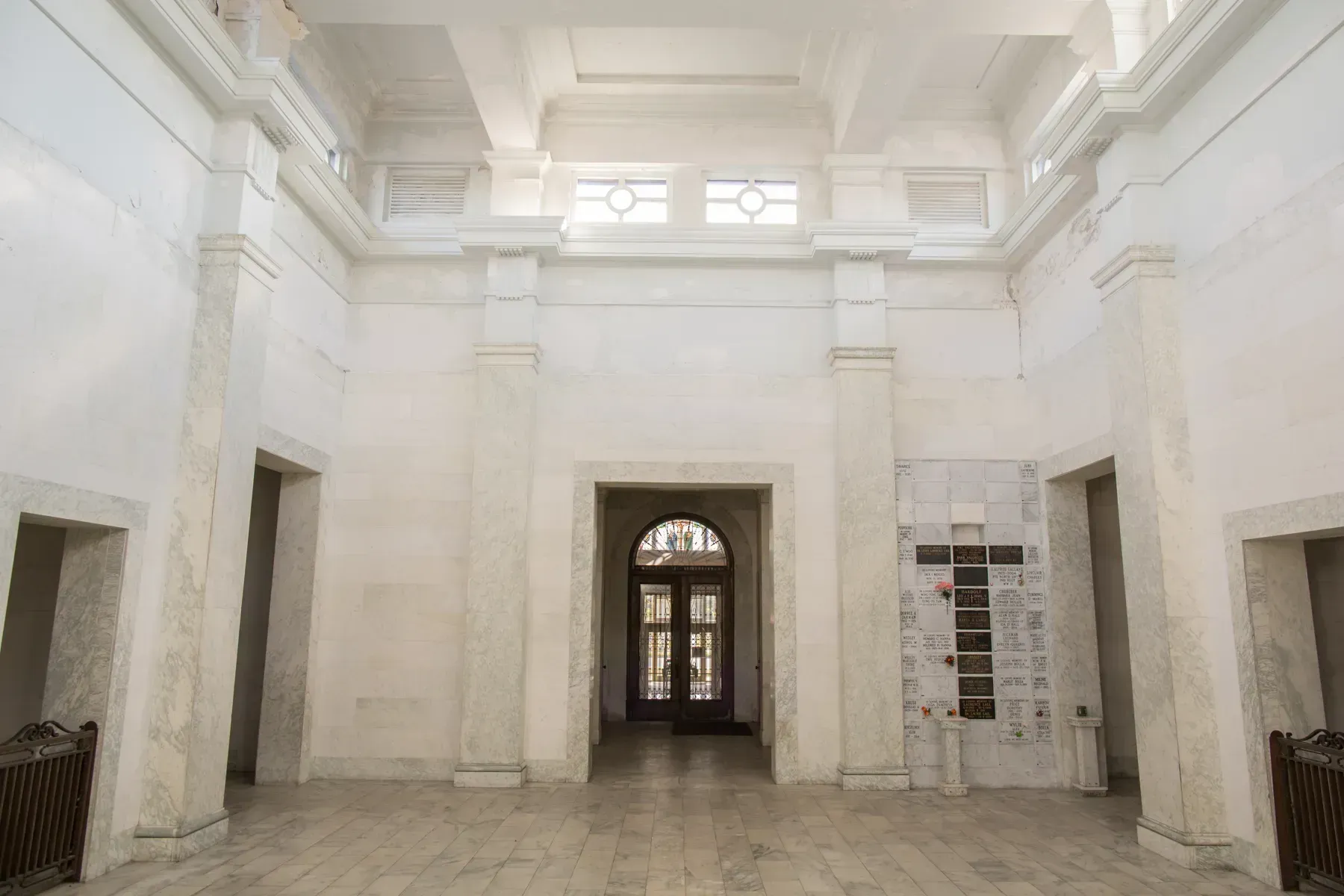 Bright white empty hall with tall columns, ornate ceiling, and a central doorway