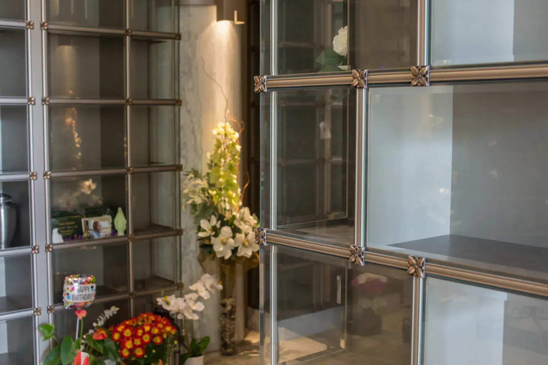 Funeral home columbarium with flowers and memorial candles in glass-front niches
