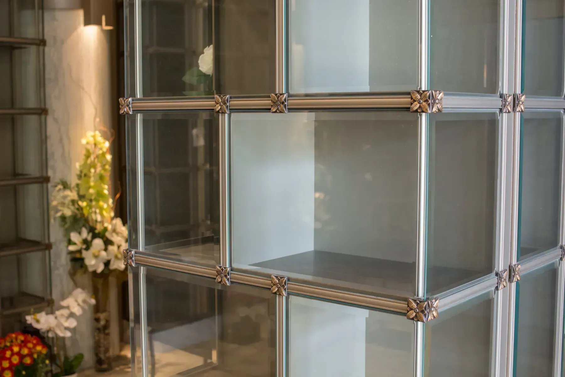 Glass shelves with gold trim beside a floral arrangement indoors