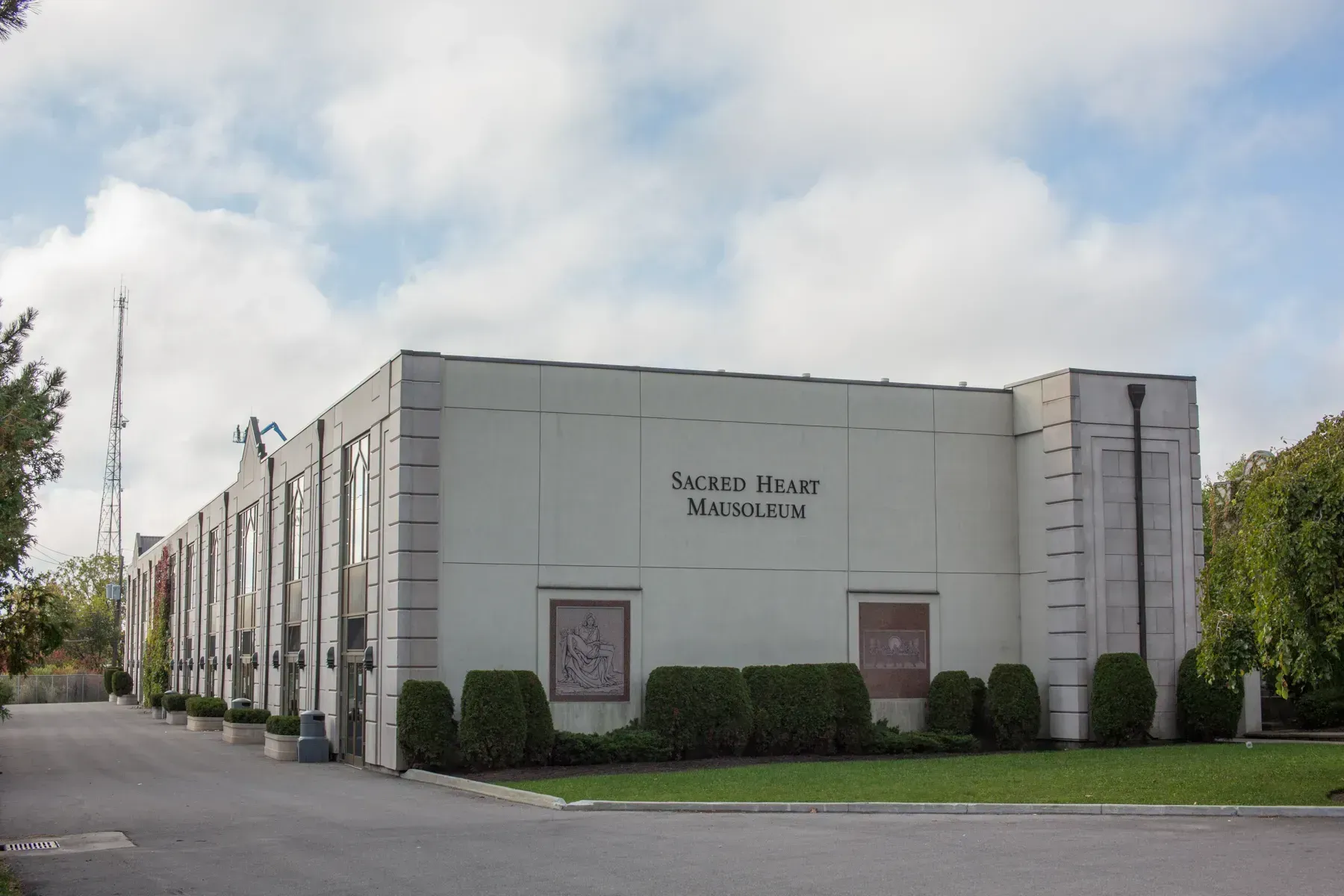 Large white office building with hedge-lined entrance and sign reading “Sermon House Bookstore”