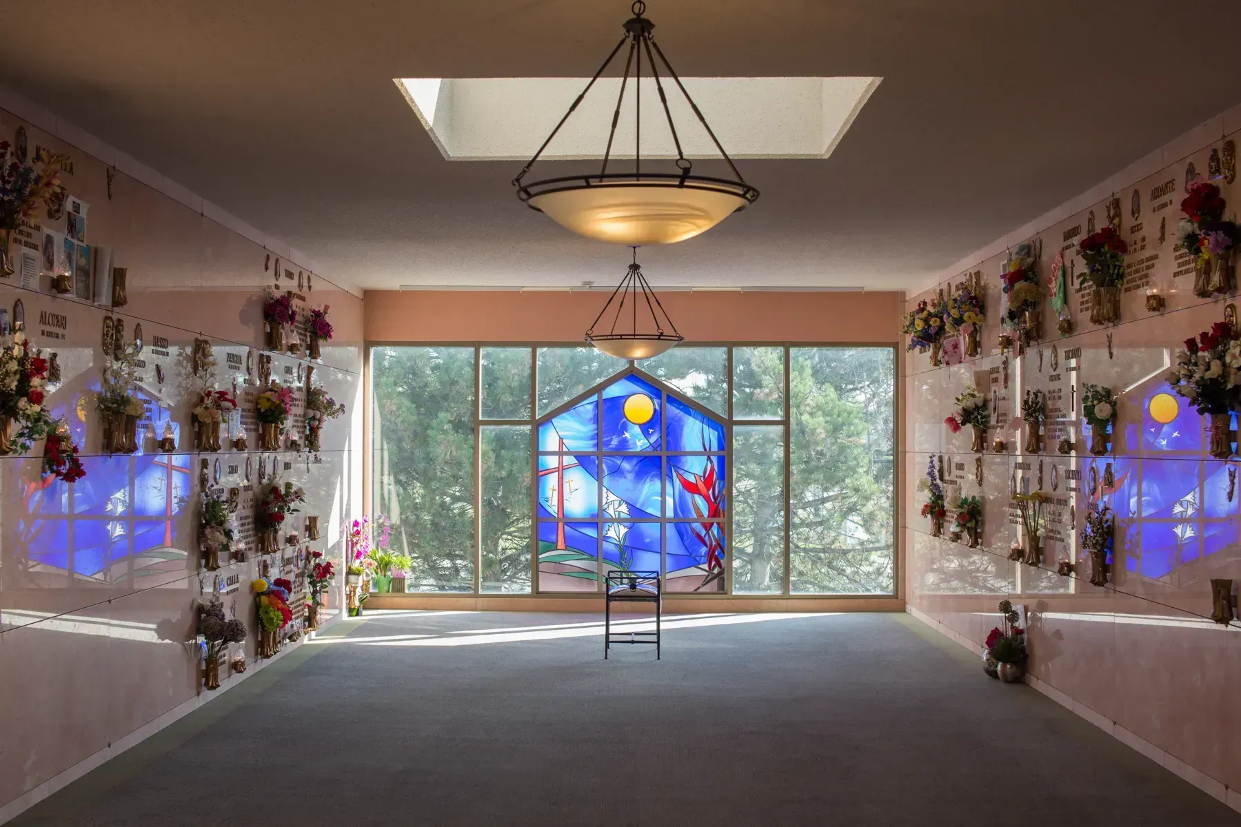 Floral-themed chapel interior with a blue stained-glass window and central aisle