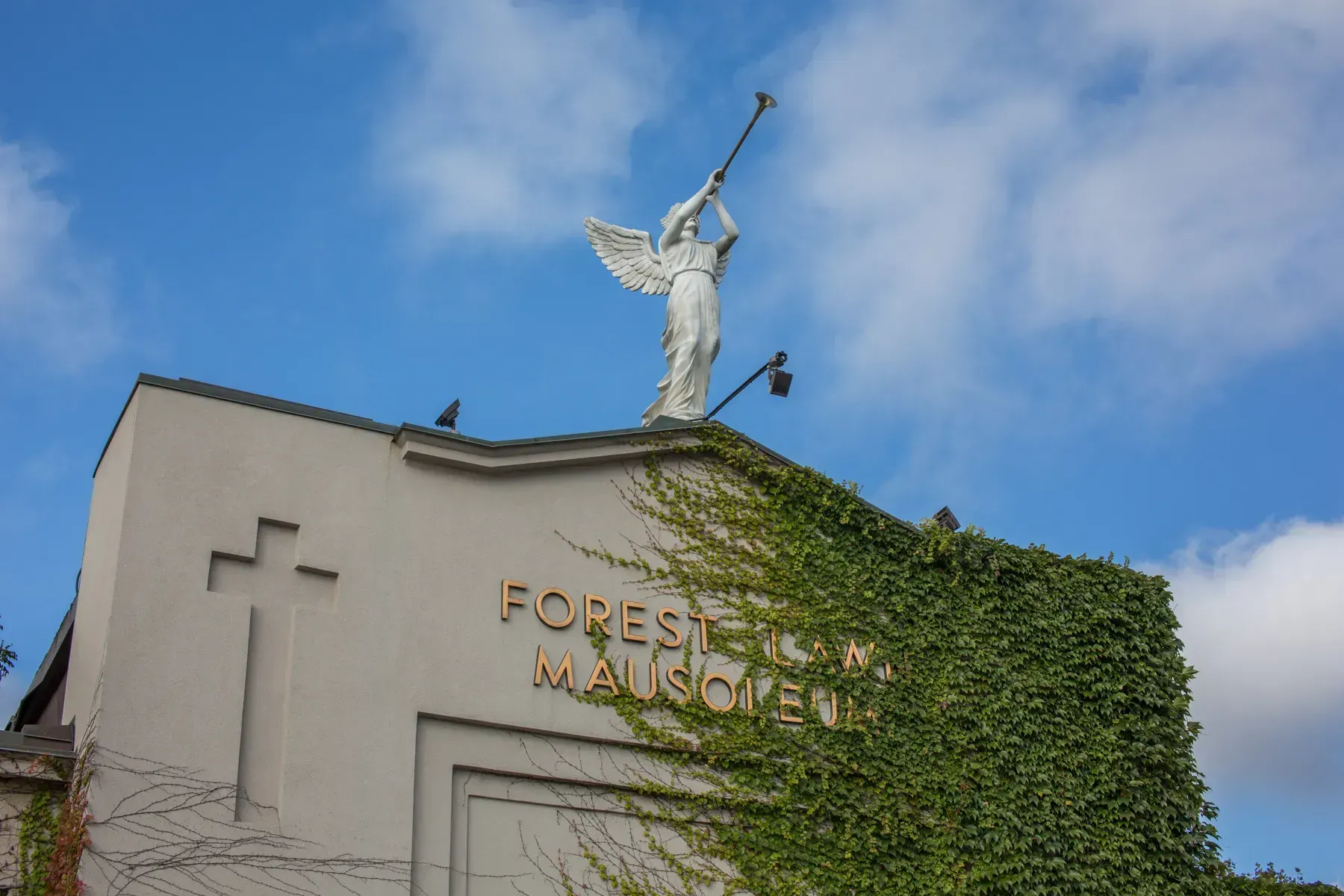Frost-covered building facade with ivy and a winged statue against a blue sky