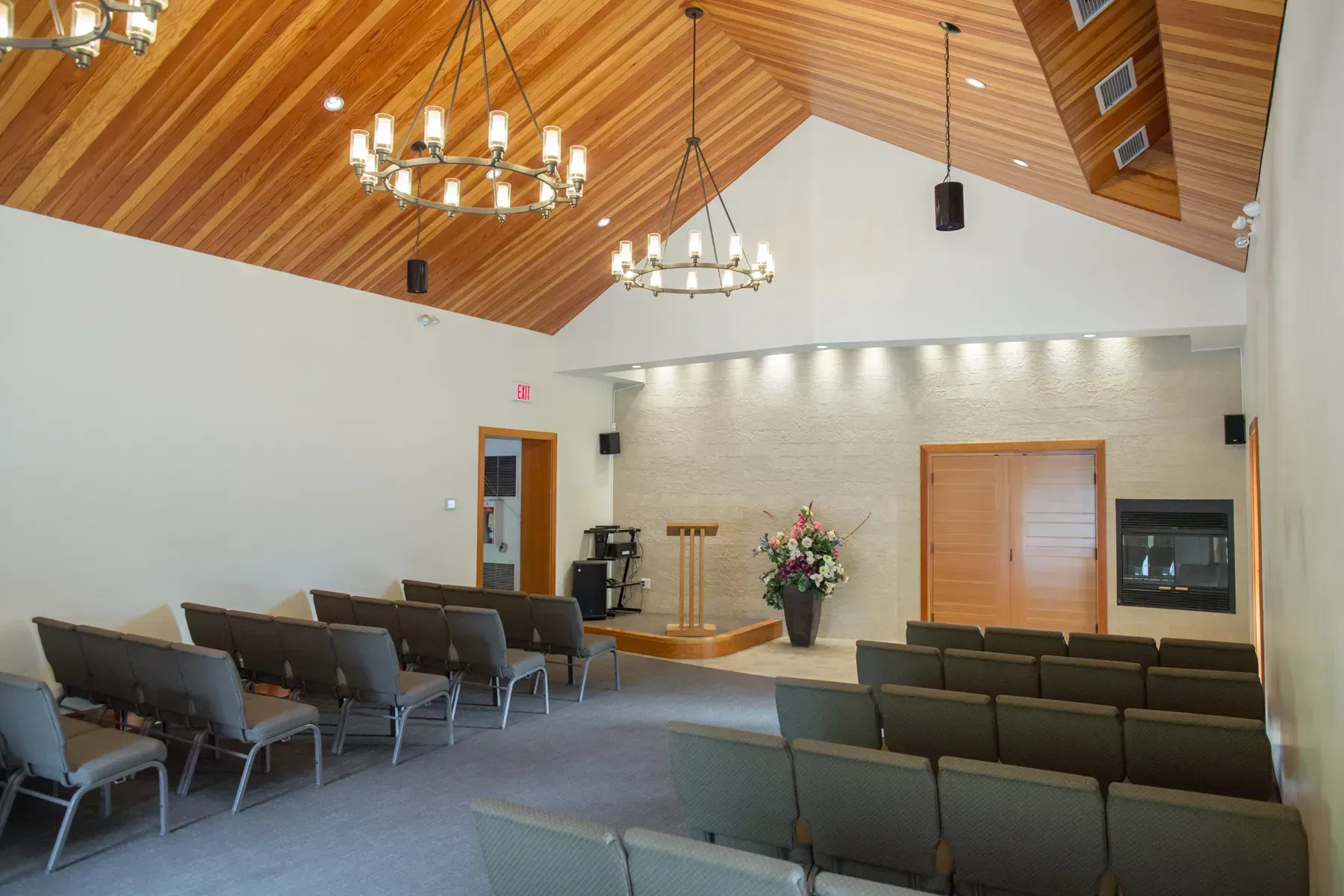 Empty church sanctuary with rows of chairs, wood-paneled vaulted ceiling, and a lectern at the front