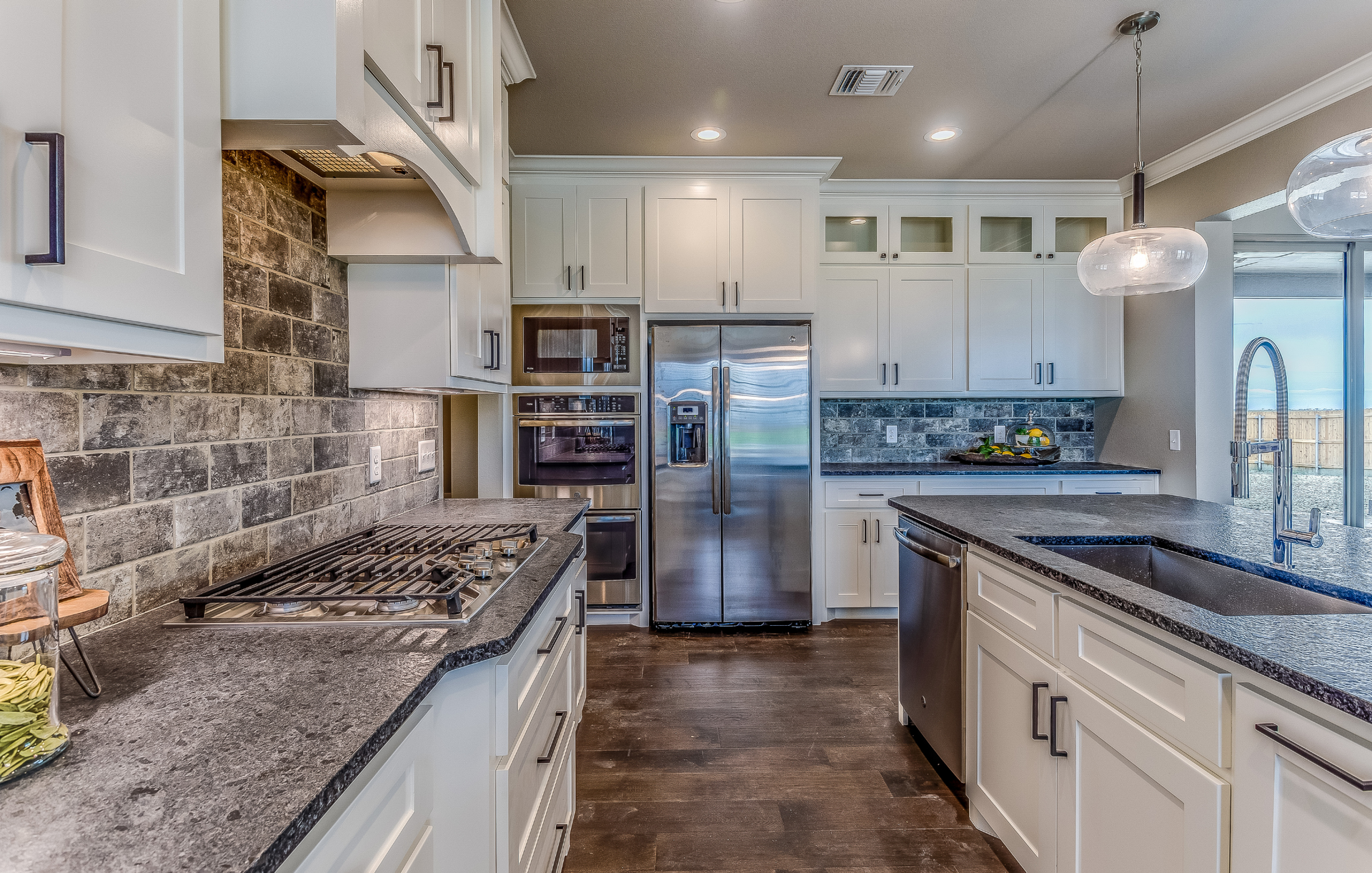 A kitchen with white cabinets , granite counter tops , stainless steel appliances and a large island.