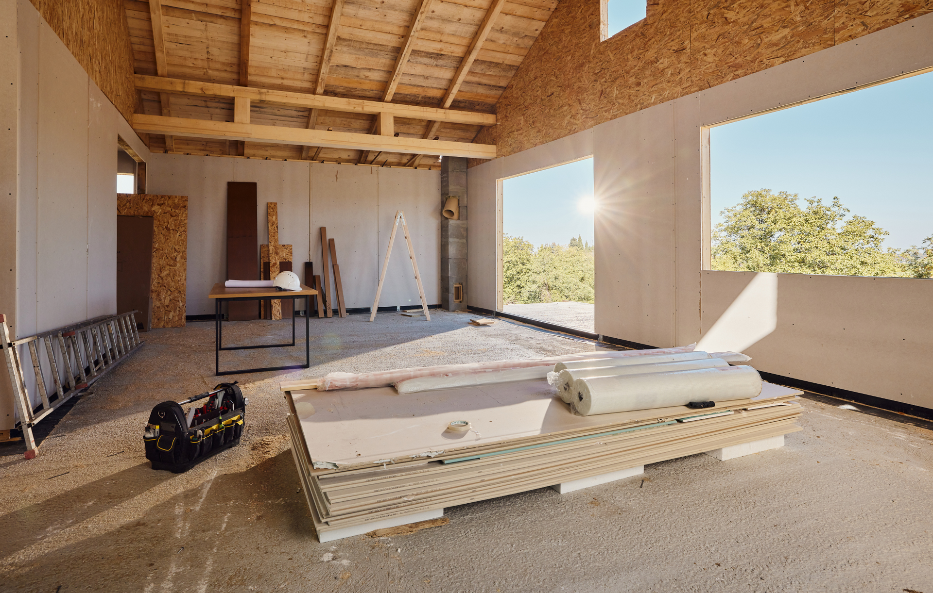 A room in a house under construction with a table and a ladder.
