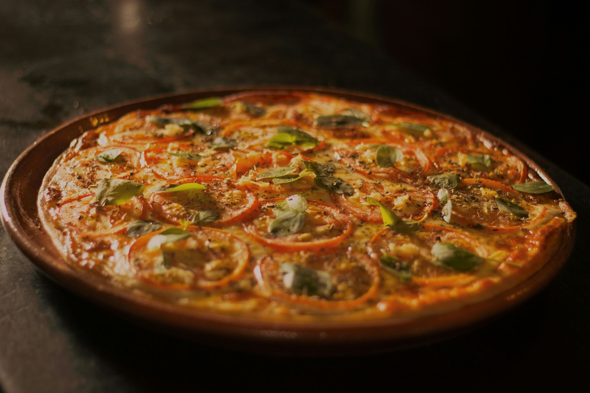 A pizza is sitting on a wooden plate on a table.