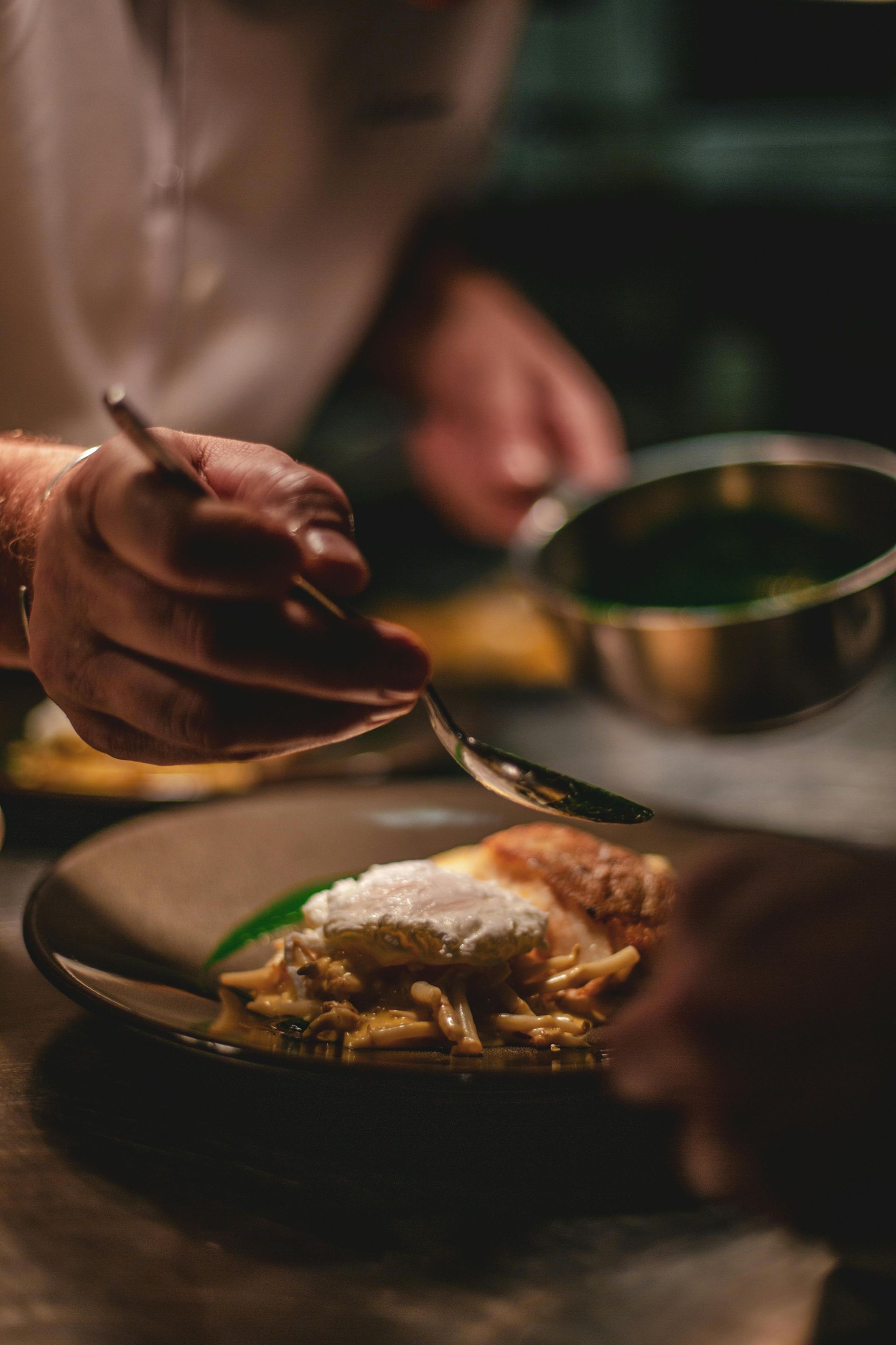 A person is preparing a plate of food with a spoon.