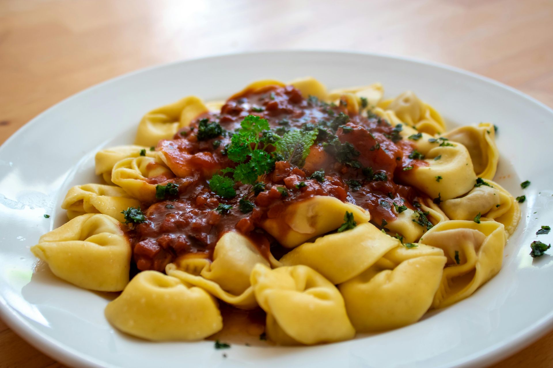 A white plate topped with pasta and sauce on a wooden table