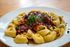 A white plate topped with pasta and sauce on a wooden table
