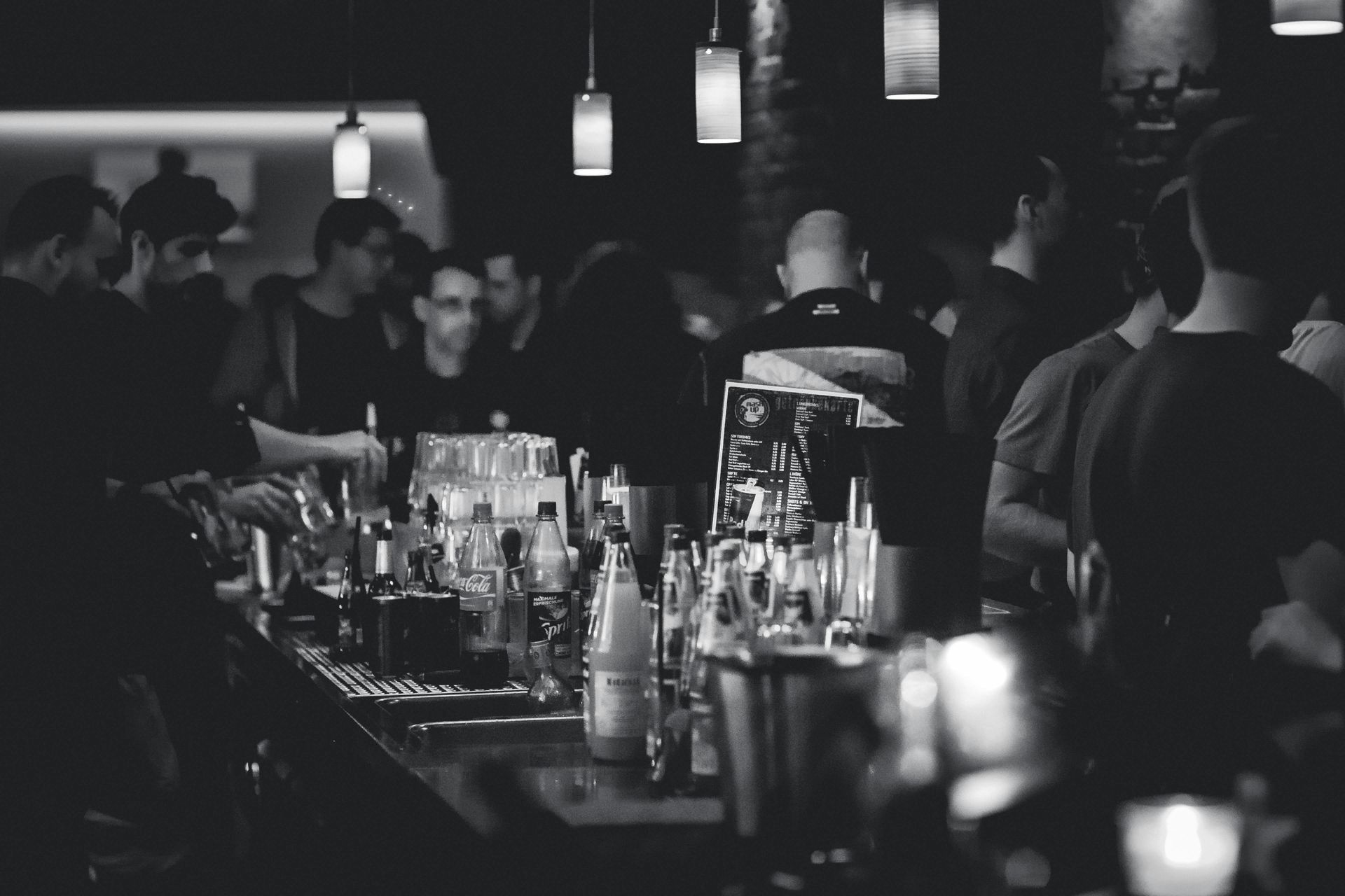 A black and white photo of a bar filled with people.