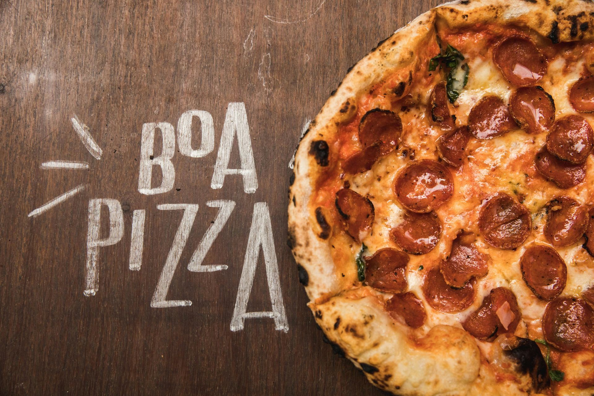 A pepperoni pizza is sitting on a wooden table.