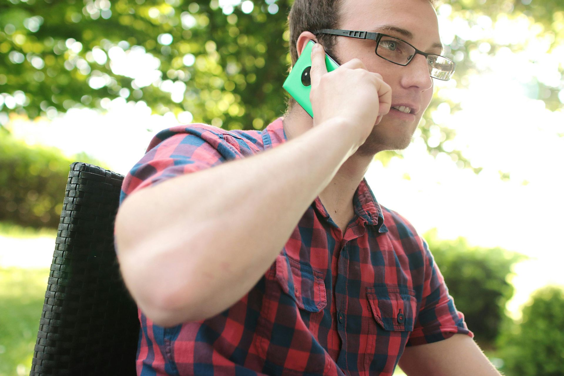A man wearing glasses is talking on a cell phone