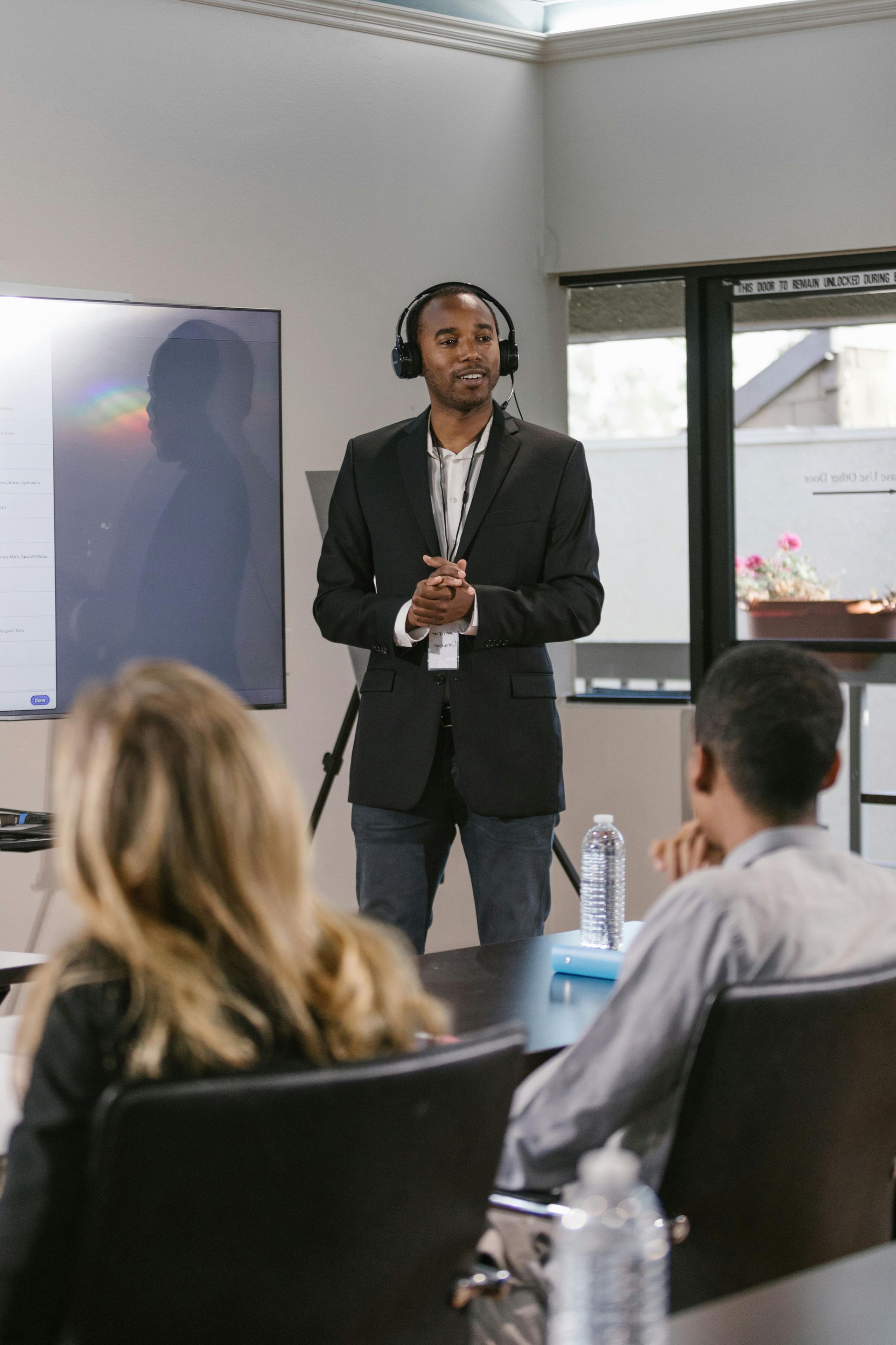 A man wearing headphones is giving a presentation to a group of people in a conference room.