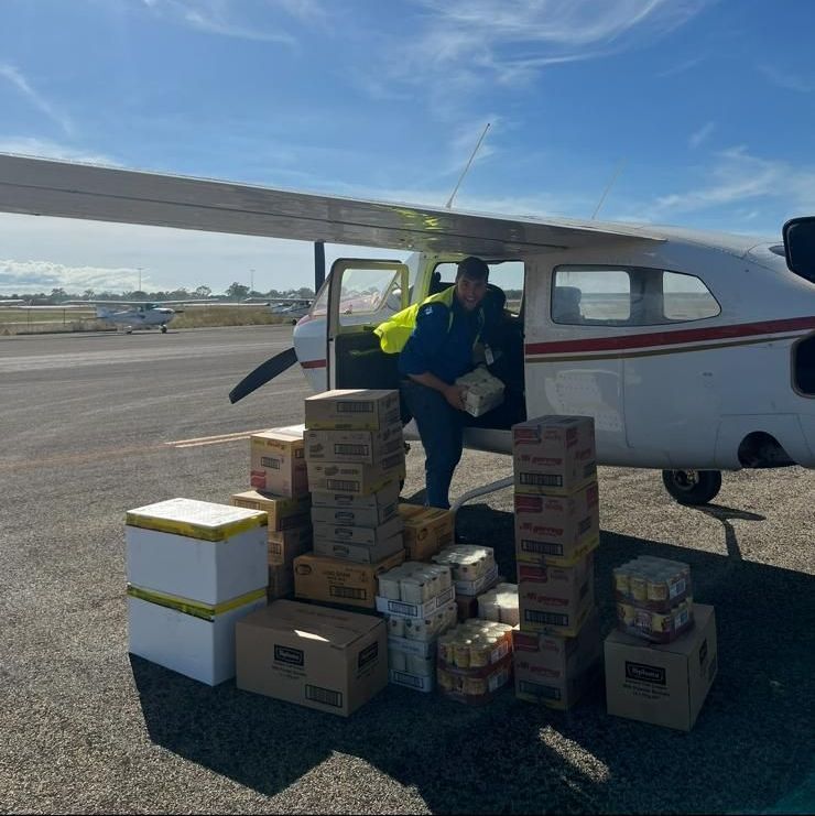 Person loads boxes of supplies into a small plane at an airfield.