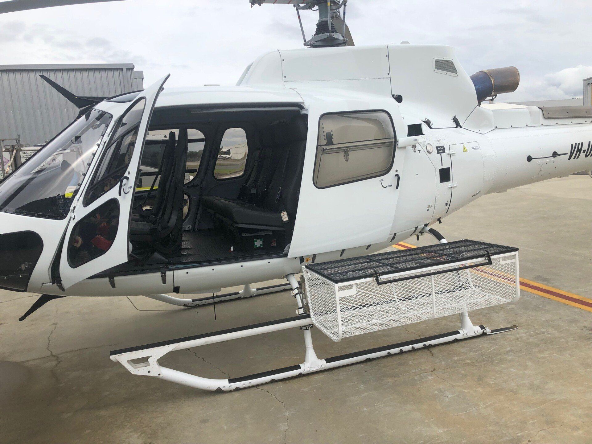 White helicopter with an open door and a large basket attached.