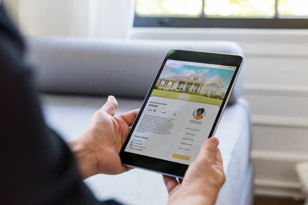 A person is holding a tablet in their hands while sitting on a couch.