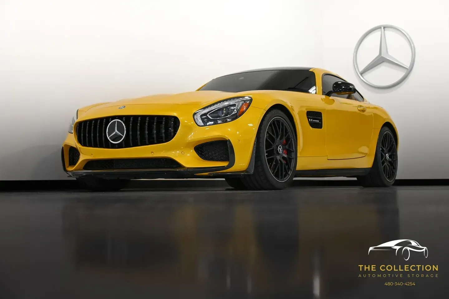 A yellow mercedes amg gt is parked in front of a white wall.