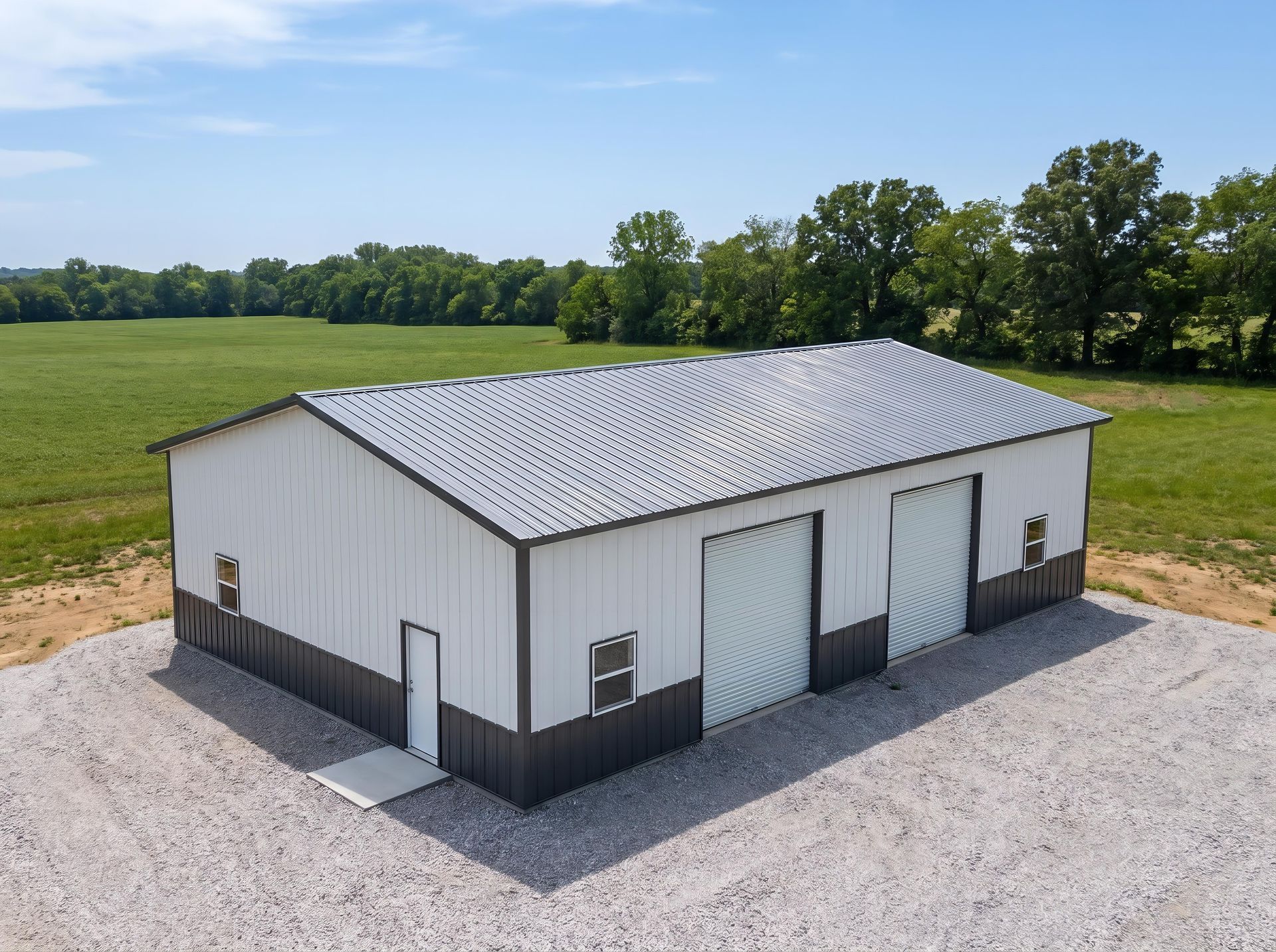 White metal barn with gray roof on gravel pad in open green field.