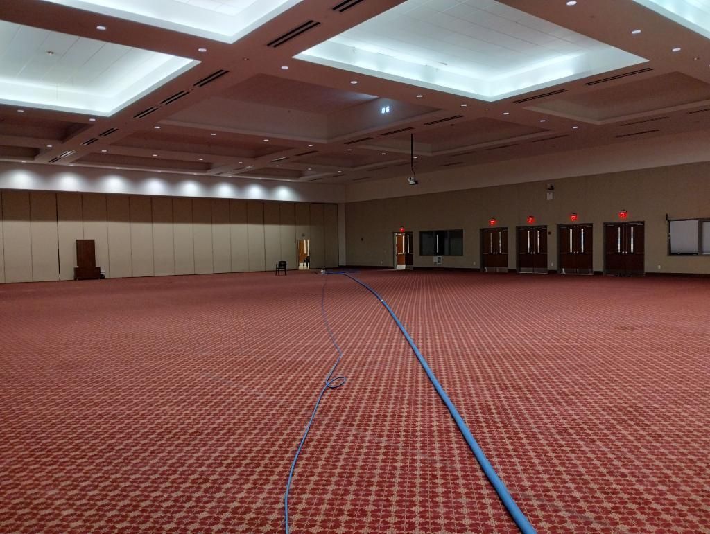 A large empty room with a red carpet and a blue hose