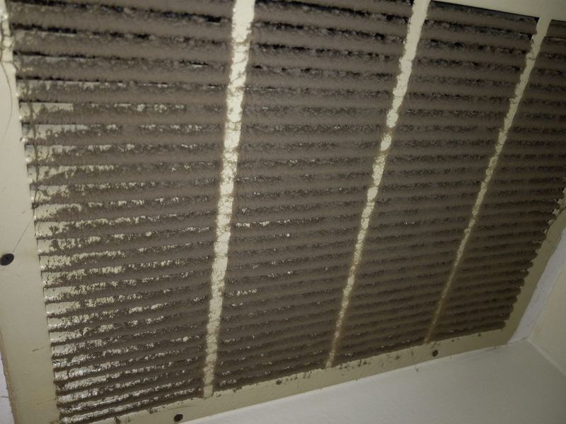 A close up of a dirty air filter on a wall