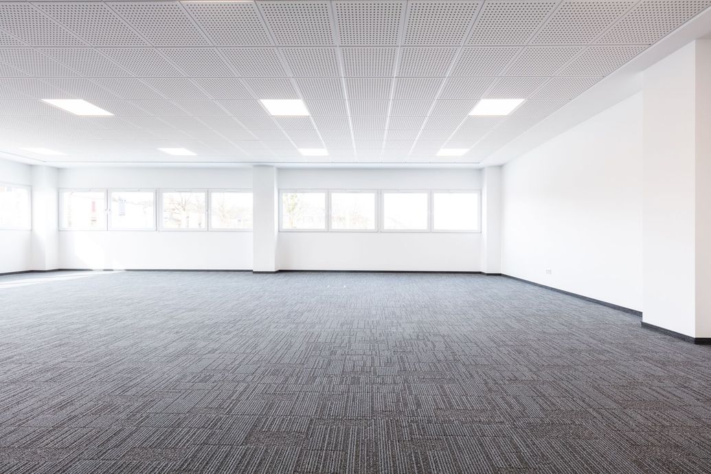 An empty office with a carpeted floor and white walls
