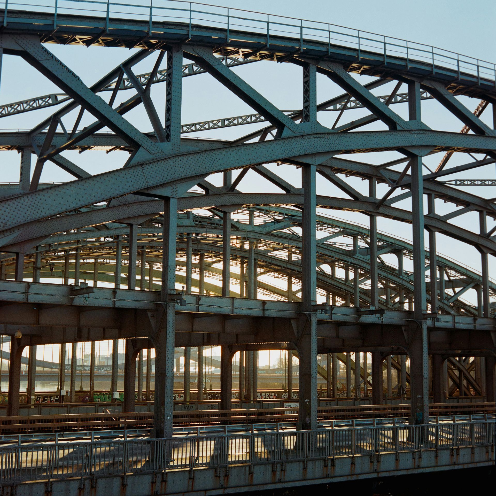 Steel bridge framework in Denver with curved beams and railings over water at sunset