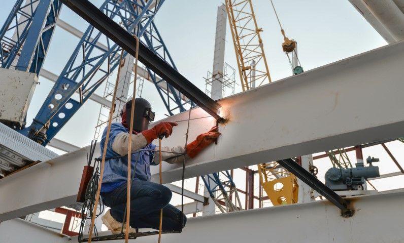 A scene at a commercial building site where a professional welds metal