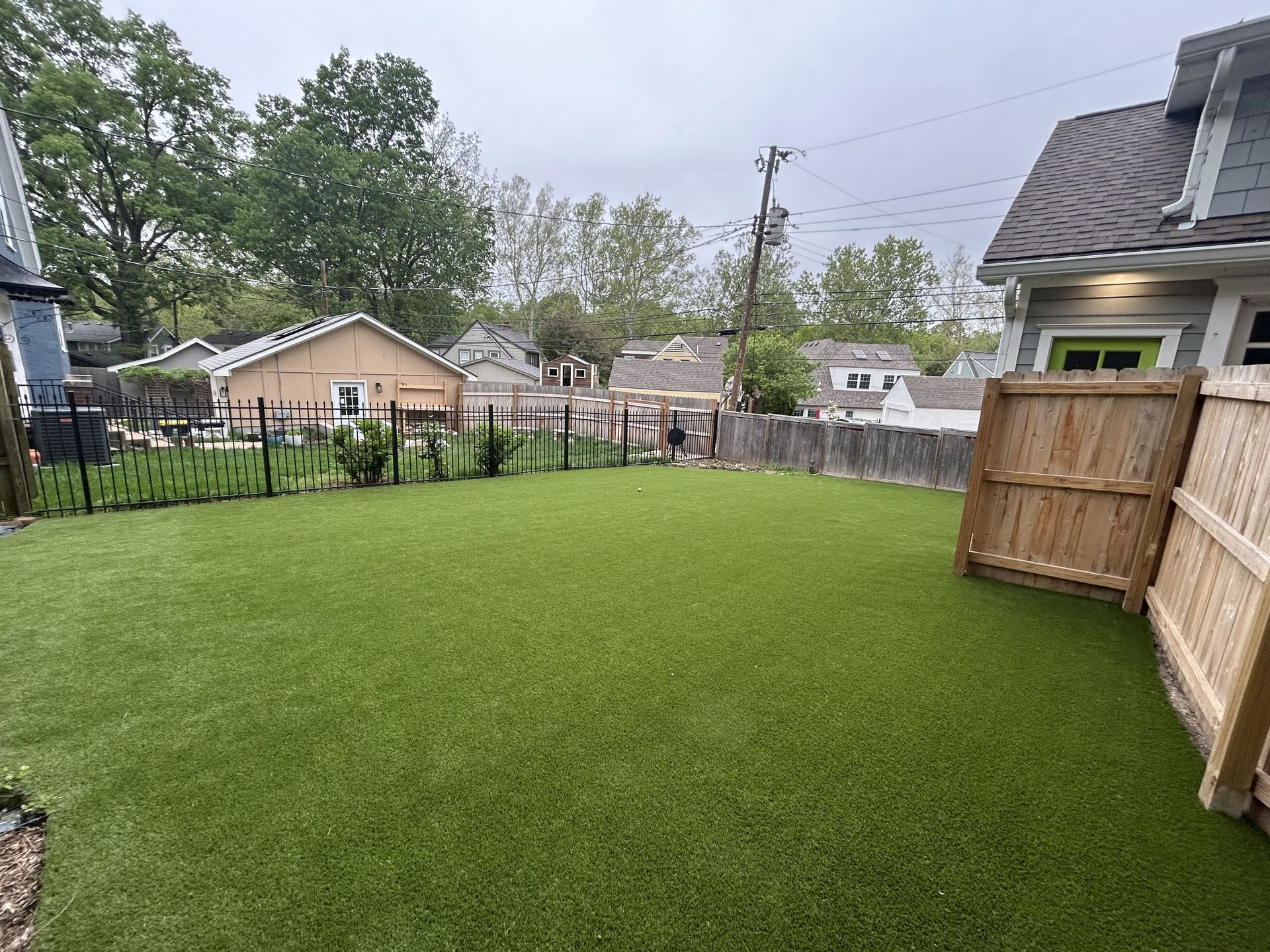 A large house with a pool and artificial turf lawn in front of it.