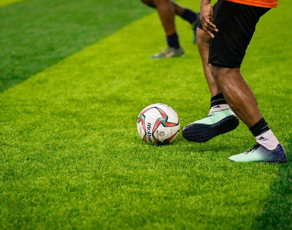 A man is kicking a soccer ball on a field.
