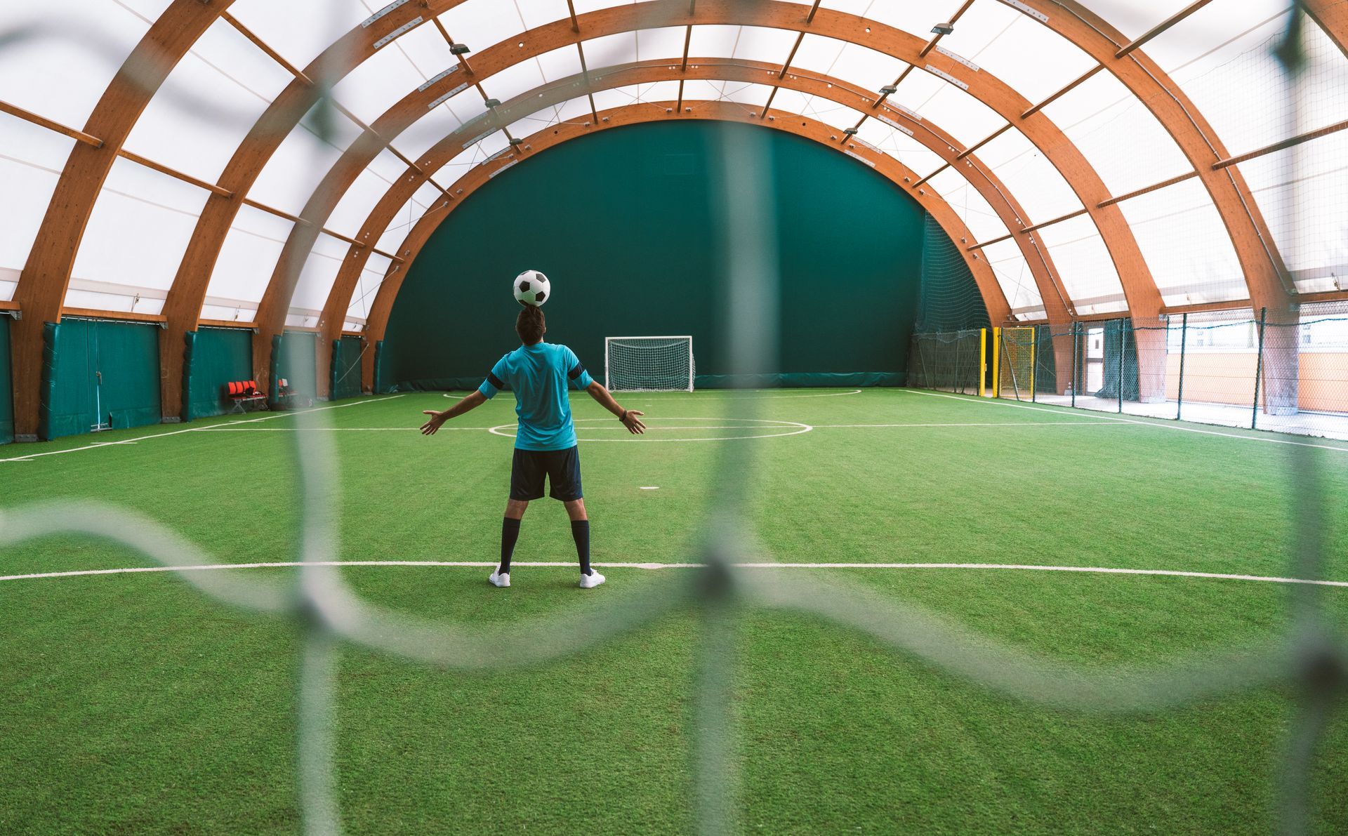 A man is standing on a soccer field with a soccer ball on his head.