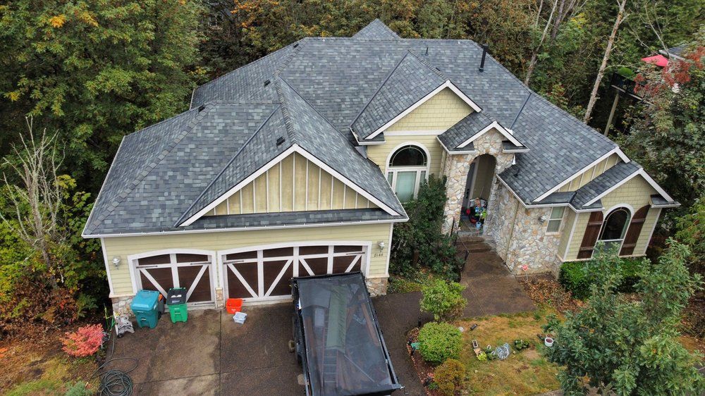 Beige house with gray roof, stone accents, and a black vehicle in the driveway.